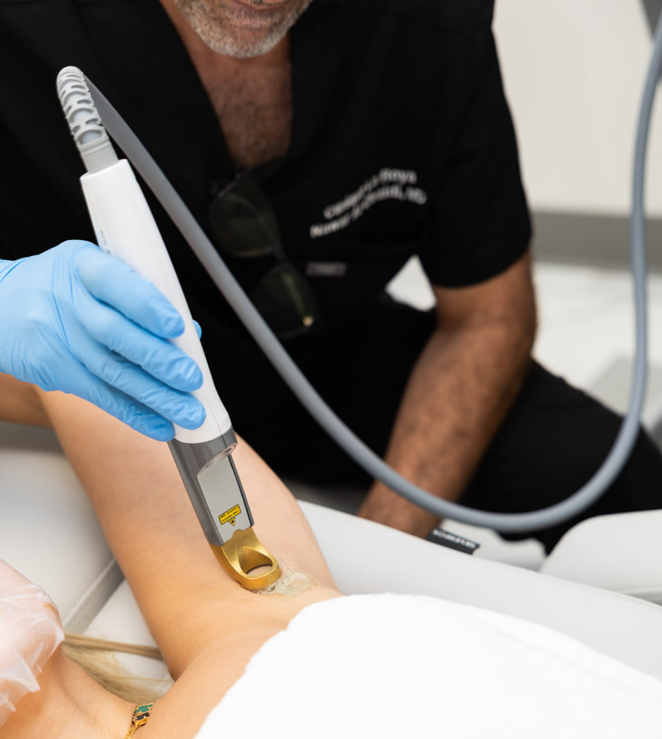 Dr. Nawar Al-Obaidi treating a patient's forearm with a Cutera laser handpiece at Clinique La Roya