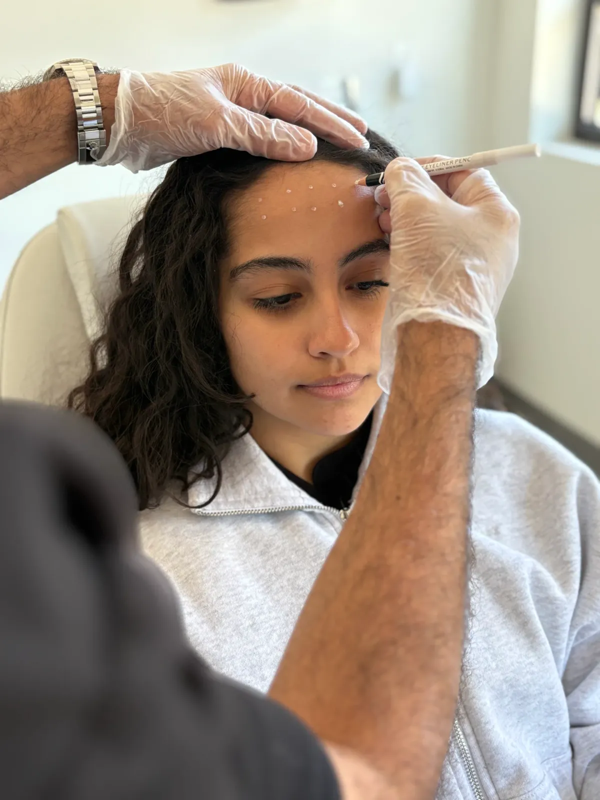 A physician marking injection points on a patient’s forehead before Botox