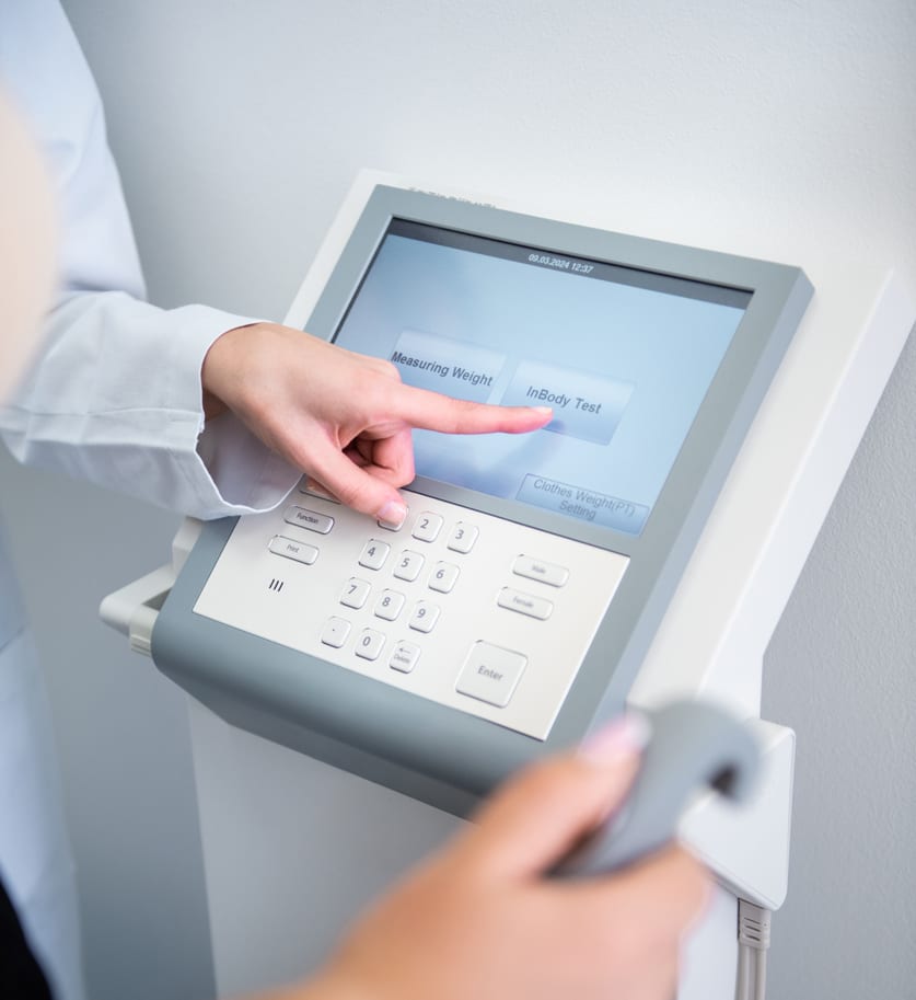 A clinician using the touchscreen of a body composition analyzer