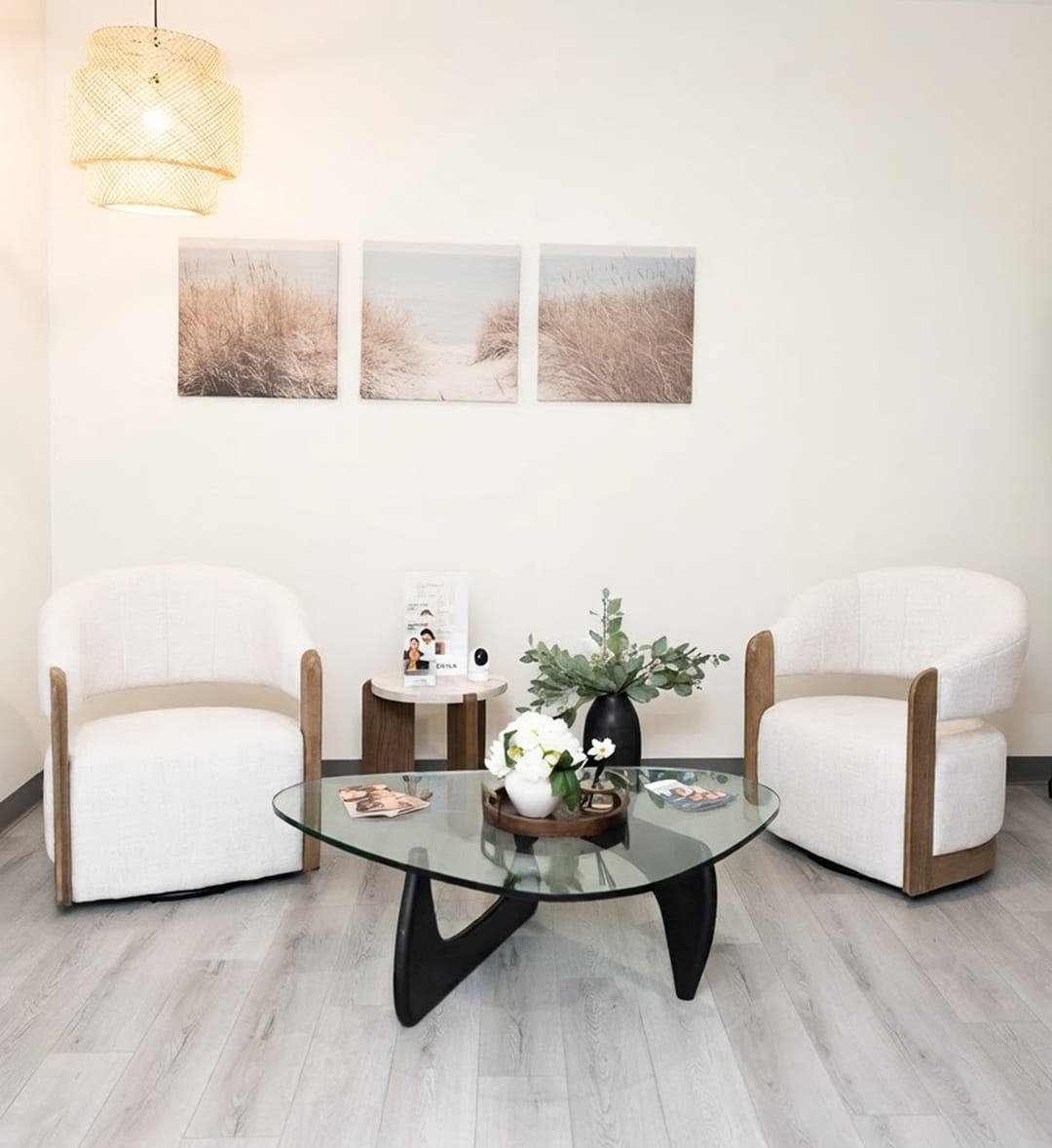 The Clinique La Roya consultation lounge with white armchairs, a glass table and a pendant light