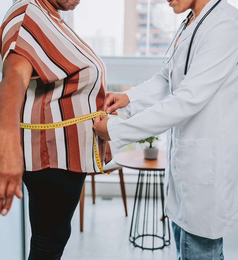 A clinician measuring a patient’s waist with a tape measure
